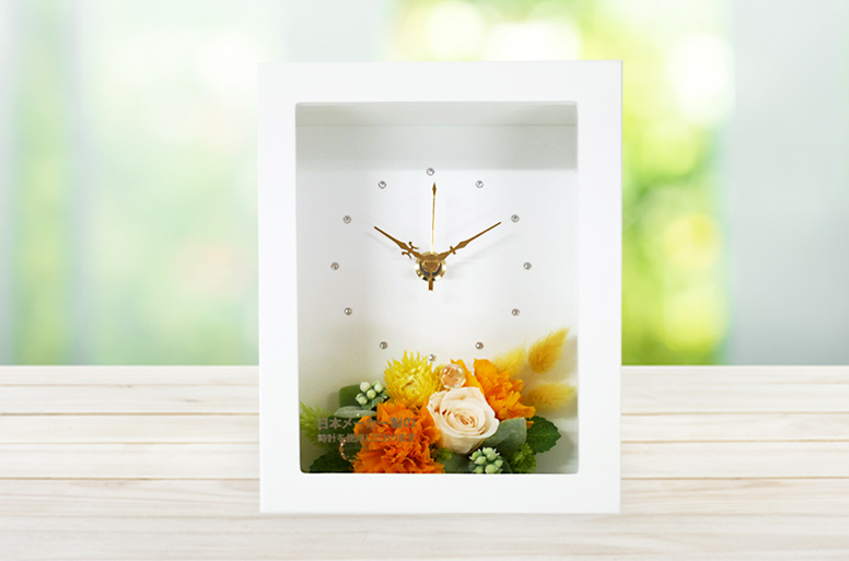 オレンジを基調としてバラ、カーネーションでアレンジした電報の「プリザーブド　clock」